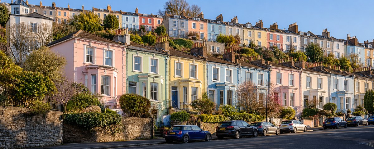 Rows of pastel-coloured terraced houses stacked up a steep hillside in Bristol, England, in clear morning light