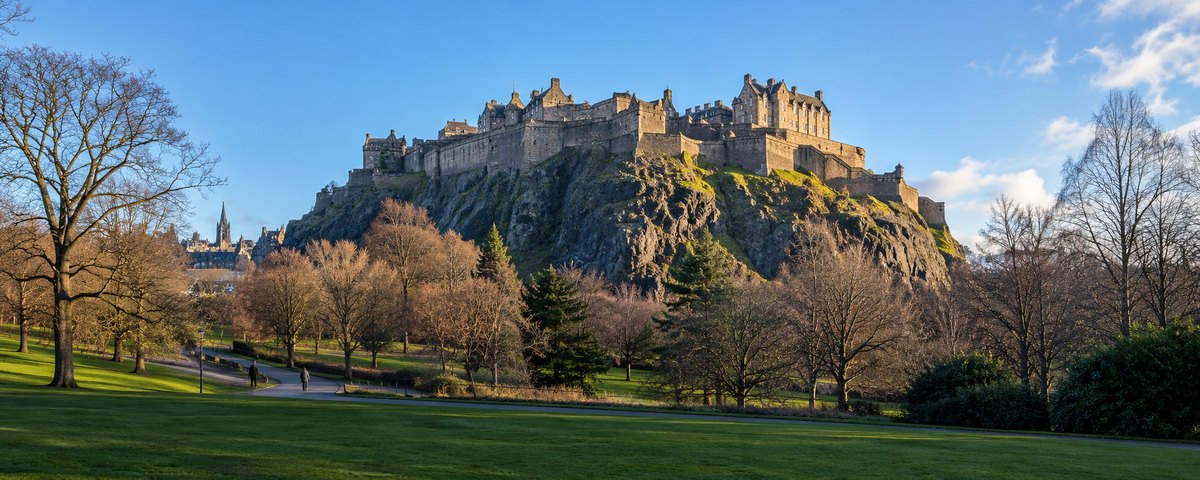 Edinburgh Castle on its volcanic crag seen across the public gardens below on a clear winter morning, Scotland